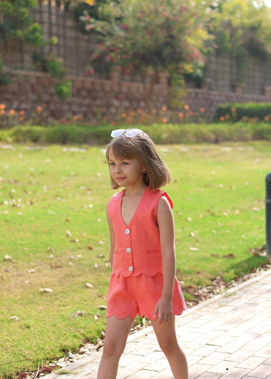 Young girl in a pink outfit standing on a pathway with greenery in the background