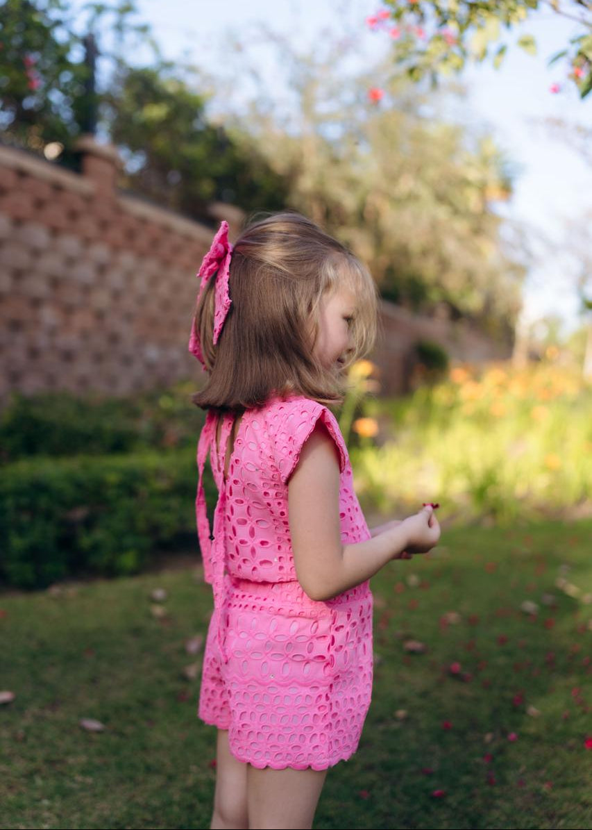 Young girl in a pink outfit standing in a garden.