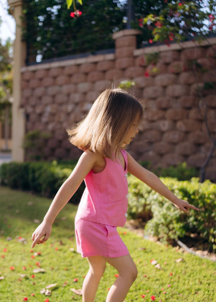 Child in a pink outfit running in a garden.