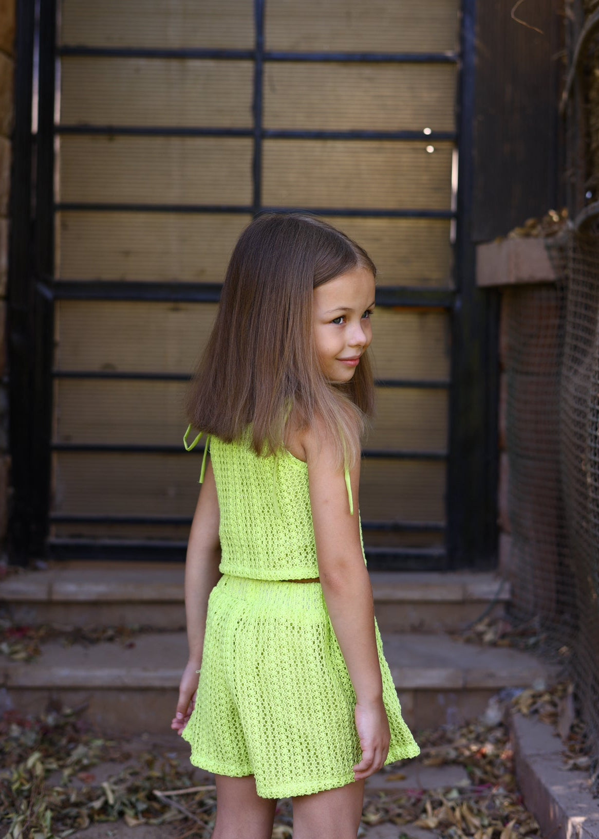 Young girl in a bright green dress standing outdoors.
