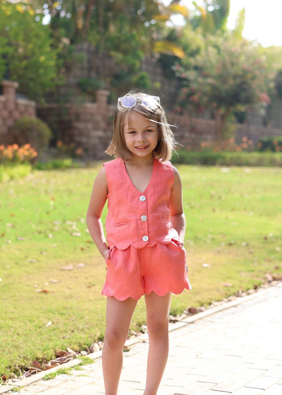 Young girl in a pink outfit standing on a path with greenery in the background