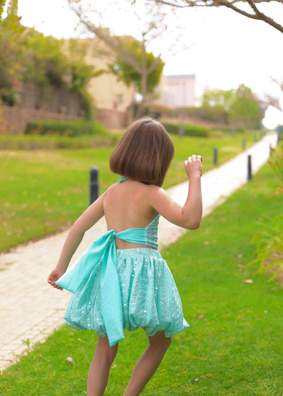 Child in a turquoise dress walking on a path in a park
