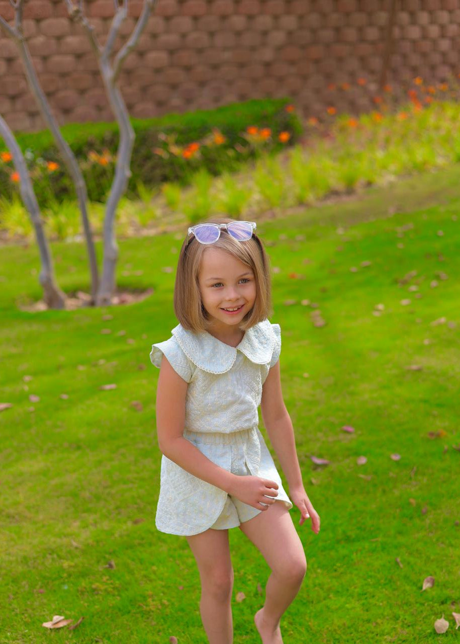 Young girl in a white outfit with a bow standing on grass